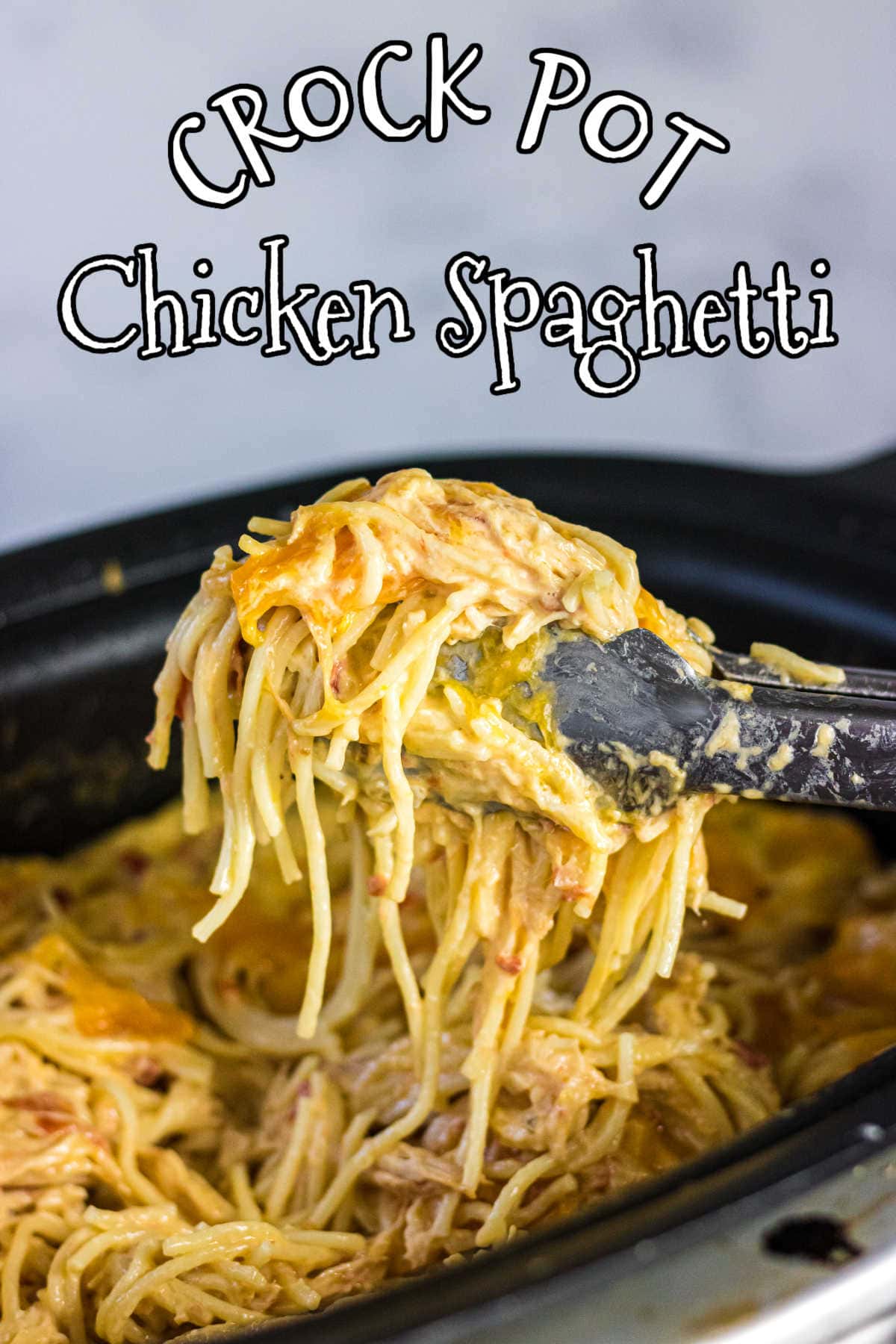 Tongs pulling a serving of chicken spaghetti from a crock pot.