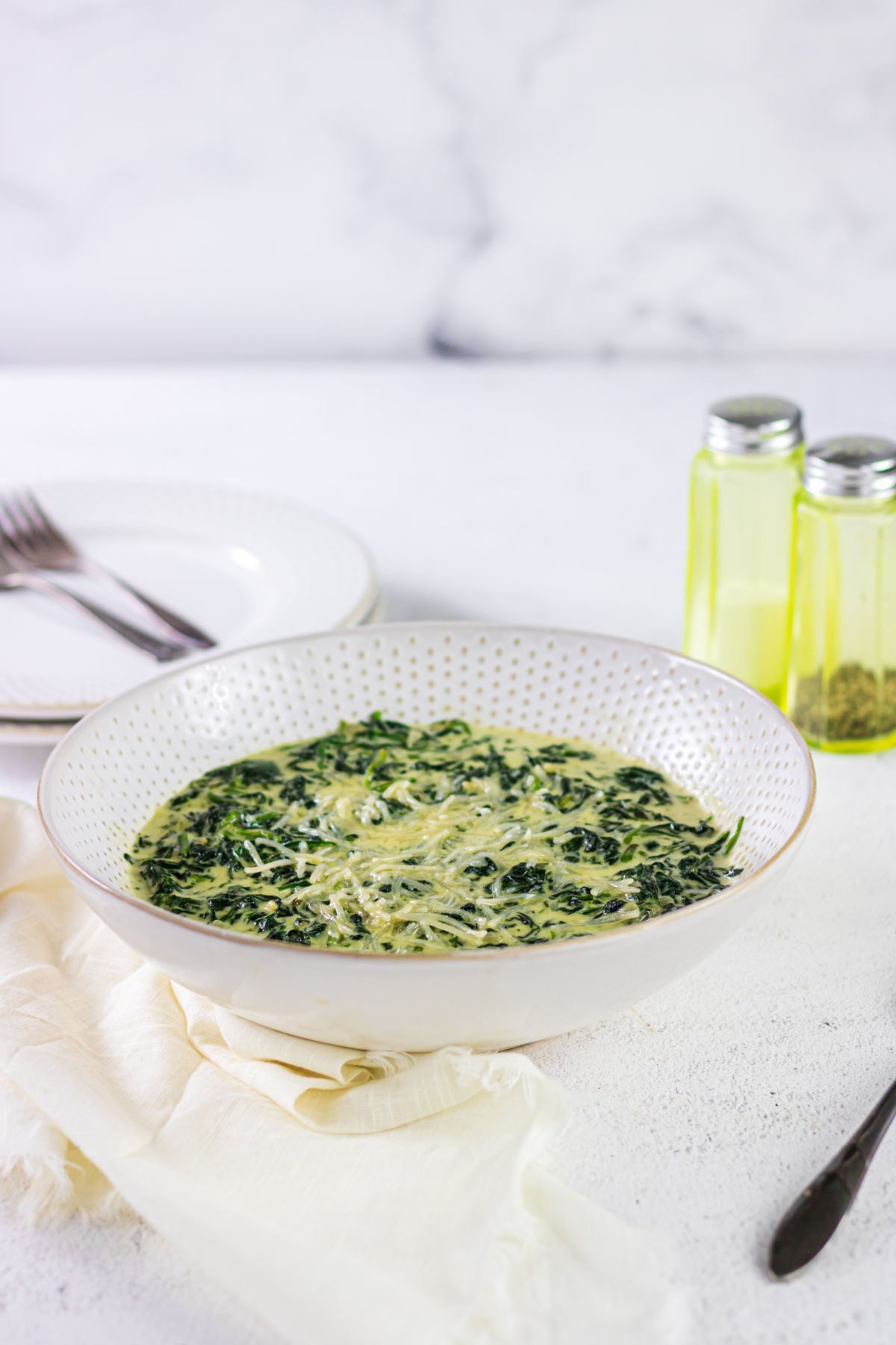 Side view of a serving bowl of spinach on the table.