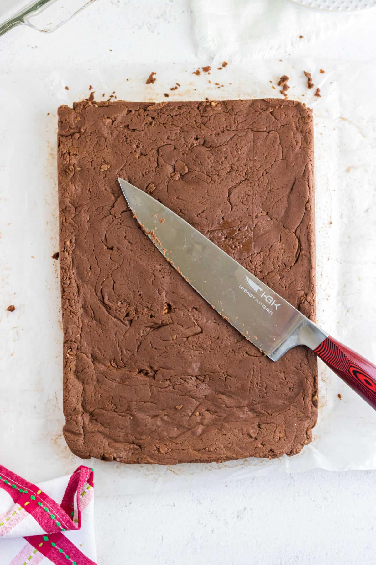 Overhead view of a slab of uncut fudge with a sharp knife on top.