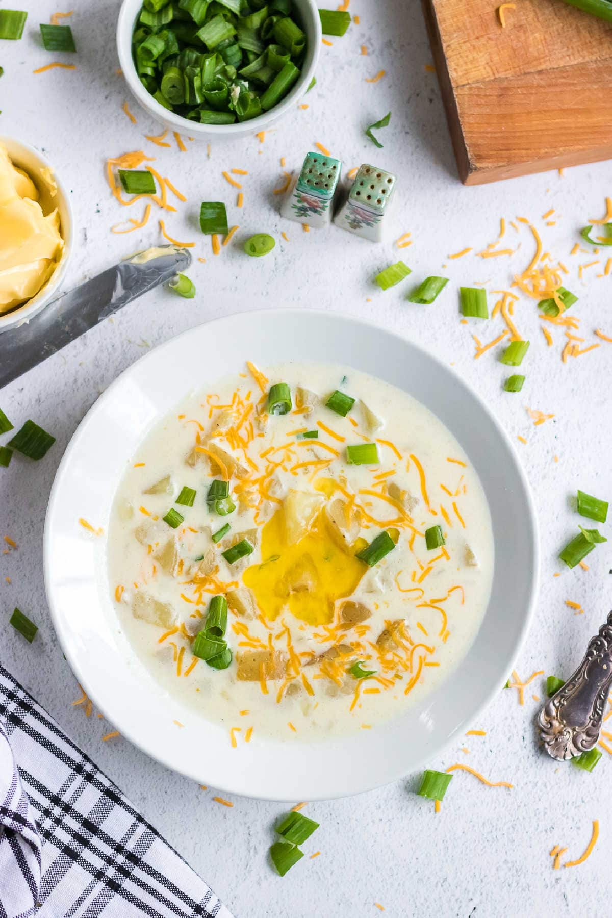 Overhead view of a bowl of potato soup garnished with green onions.