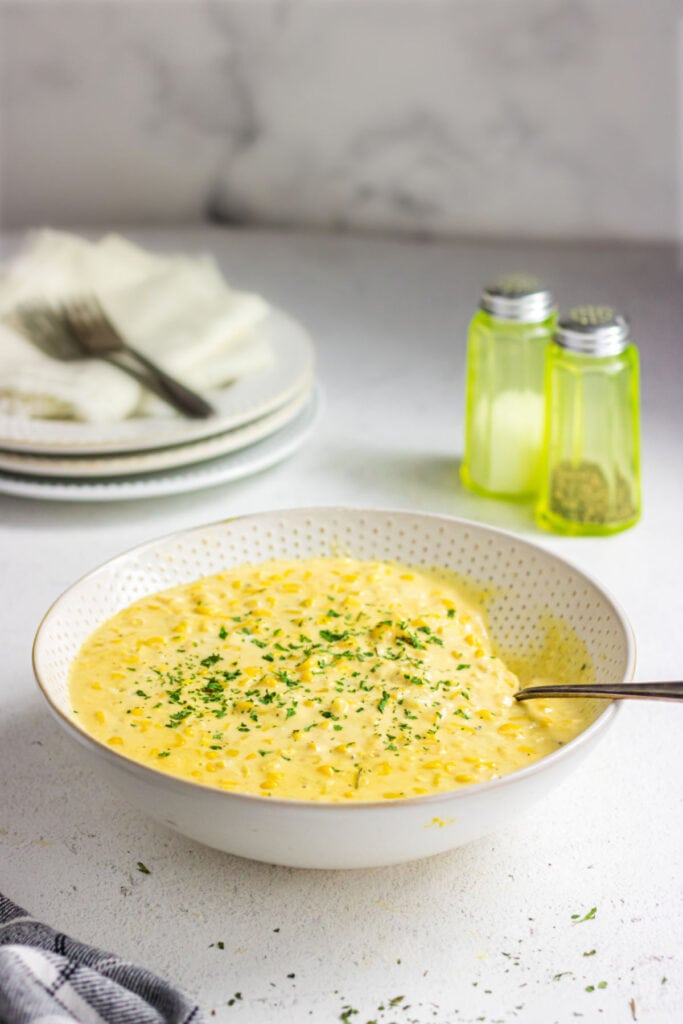 Side view of finished creamed corn in a white dish.