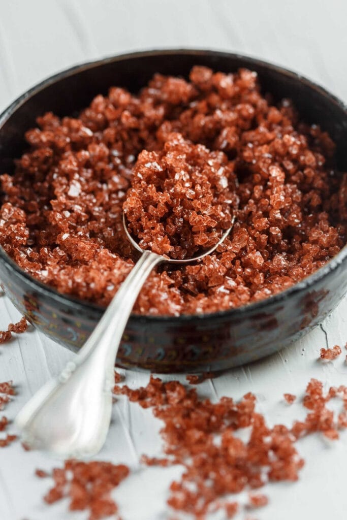 A bowl of red salt with a spoon in it.