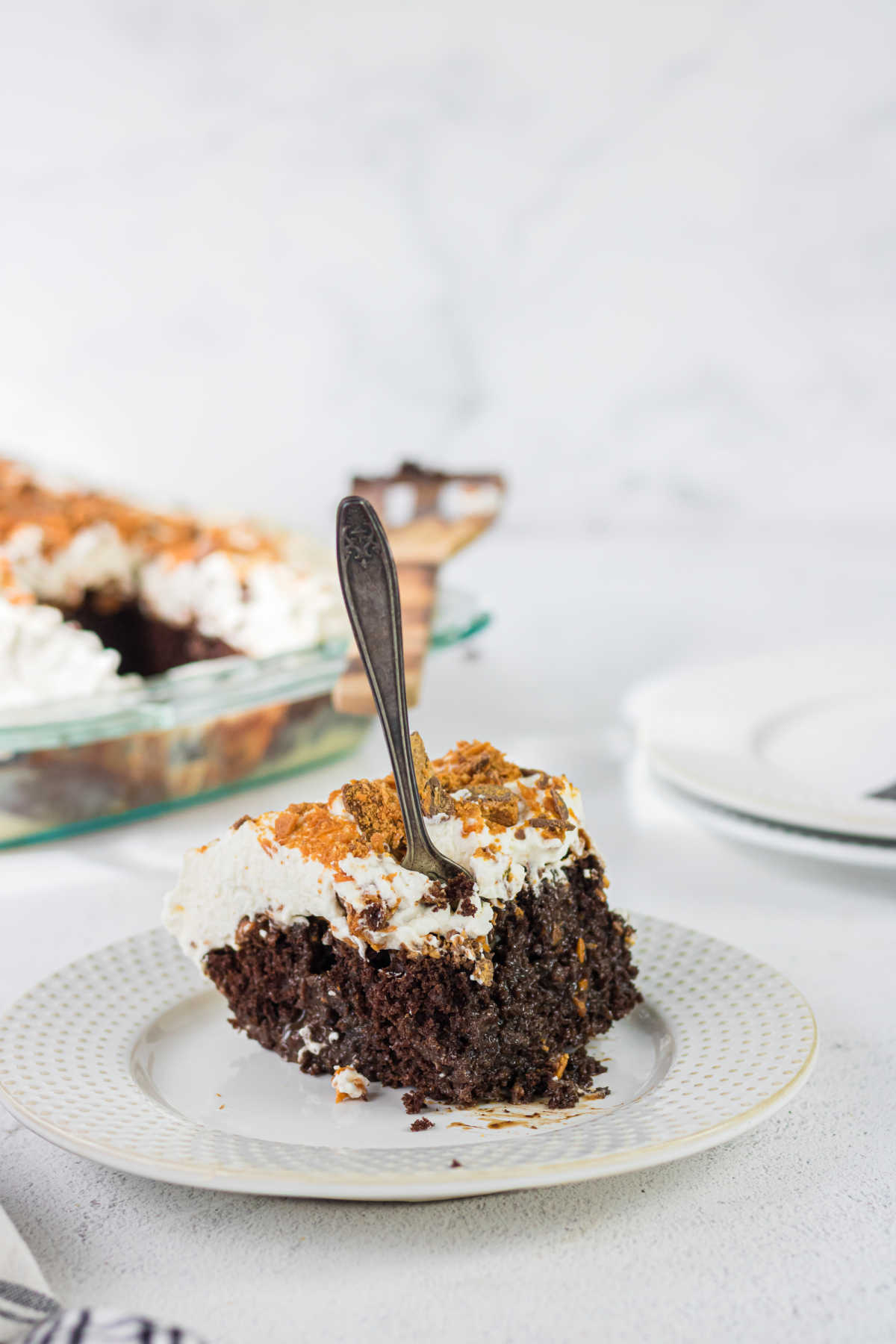 A square of chocolate cake with a fork in it.