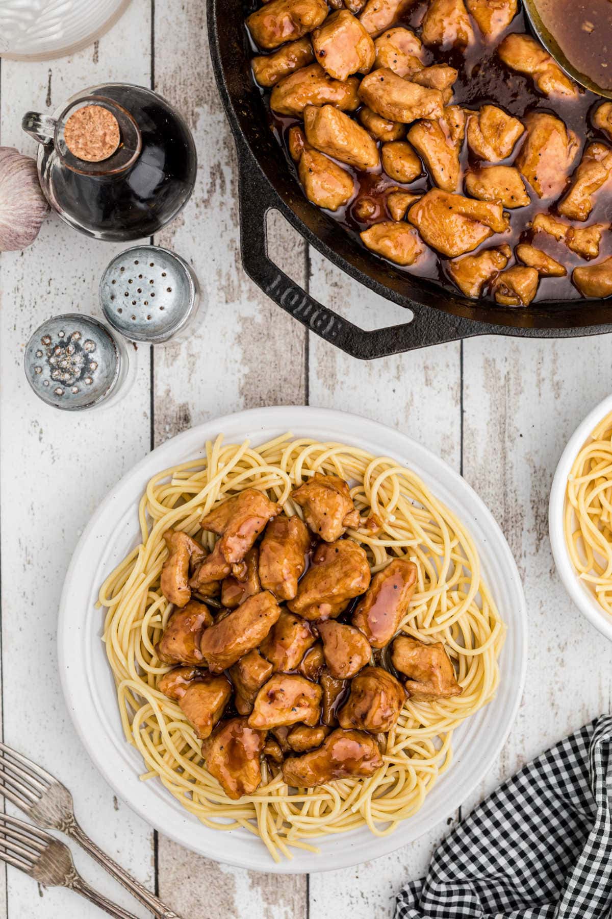 Overhead view of the chicken on a plate with a skillet in the background.