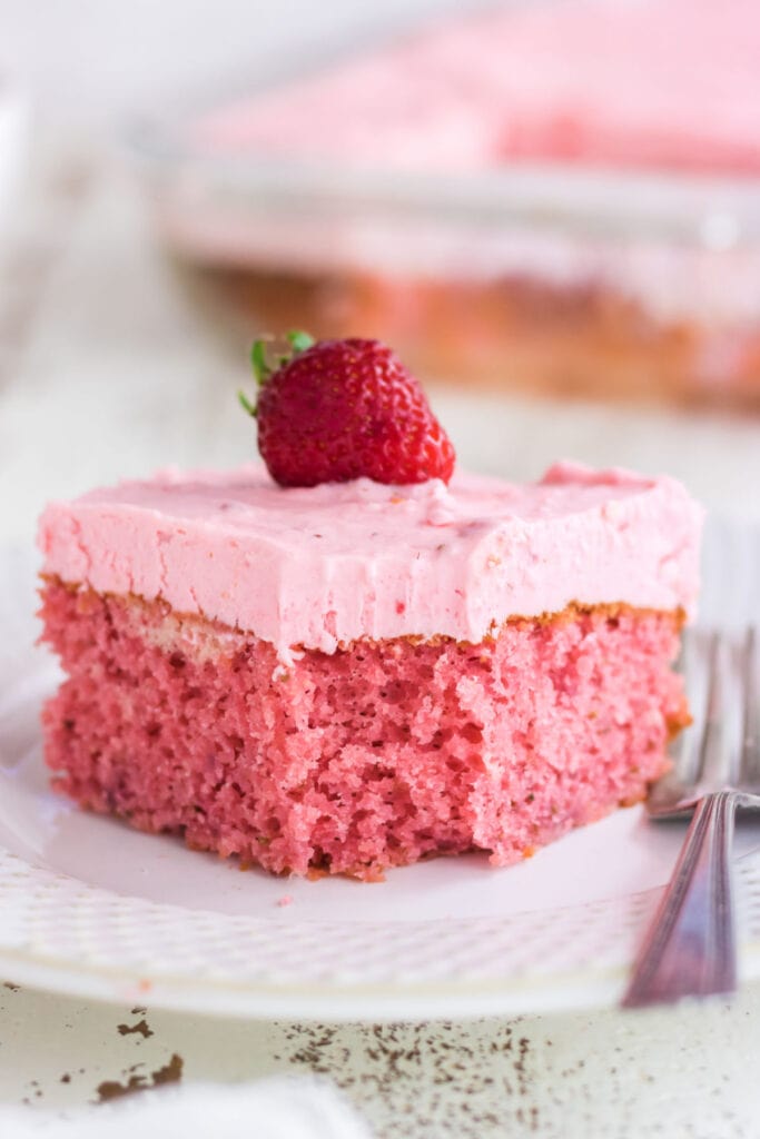 Side view of strawberry cake showing the textures of the frosting and the cake.