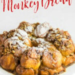 A round loaf of monkey bread dusted with powdered sugar. Title text overlay for Pinterest.