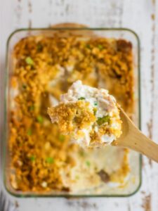 Close up of a wooden spoon serving the casserole.