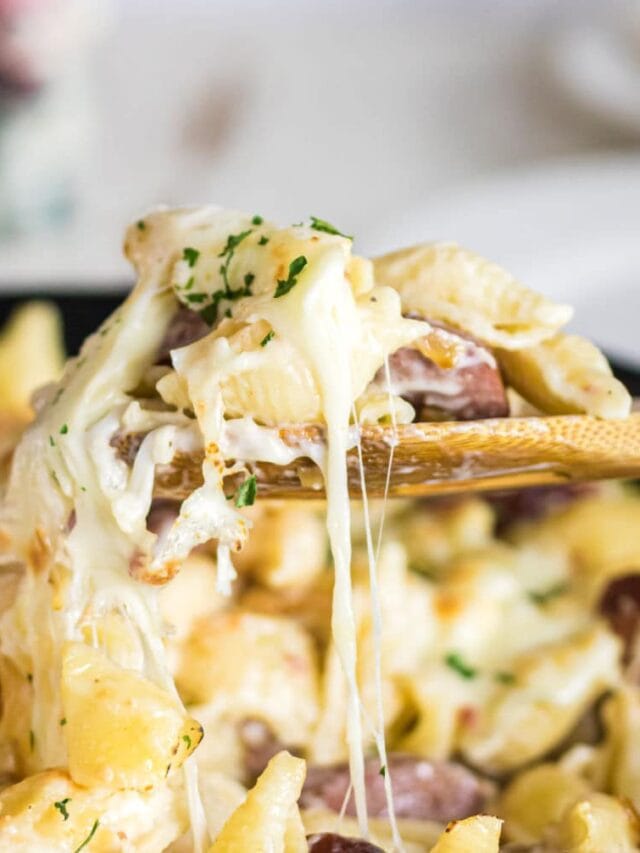 Close up of a spoonful of sausage alfredo with a text overlay for Pinterest.