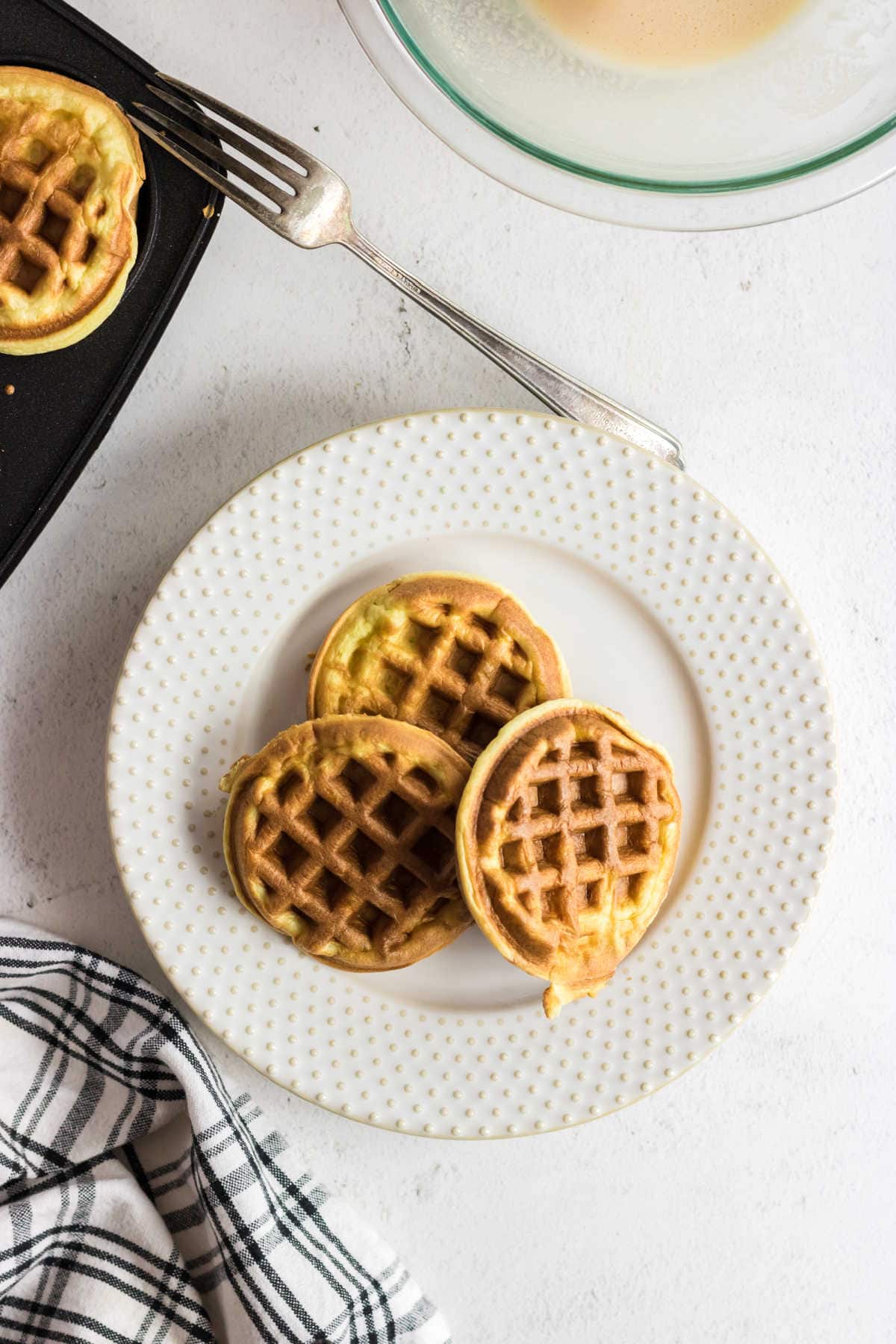 Overhead view of chaffles being removed from the waffle iron.