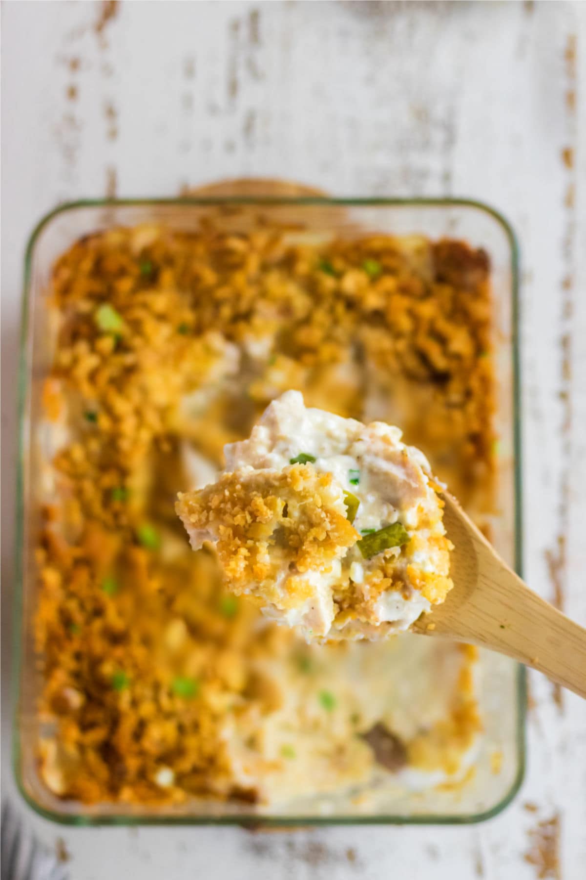 Close up of a wooden spoon serving the casserole.