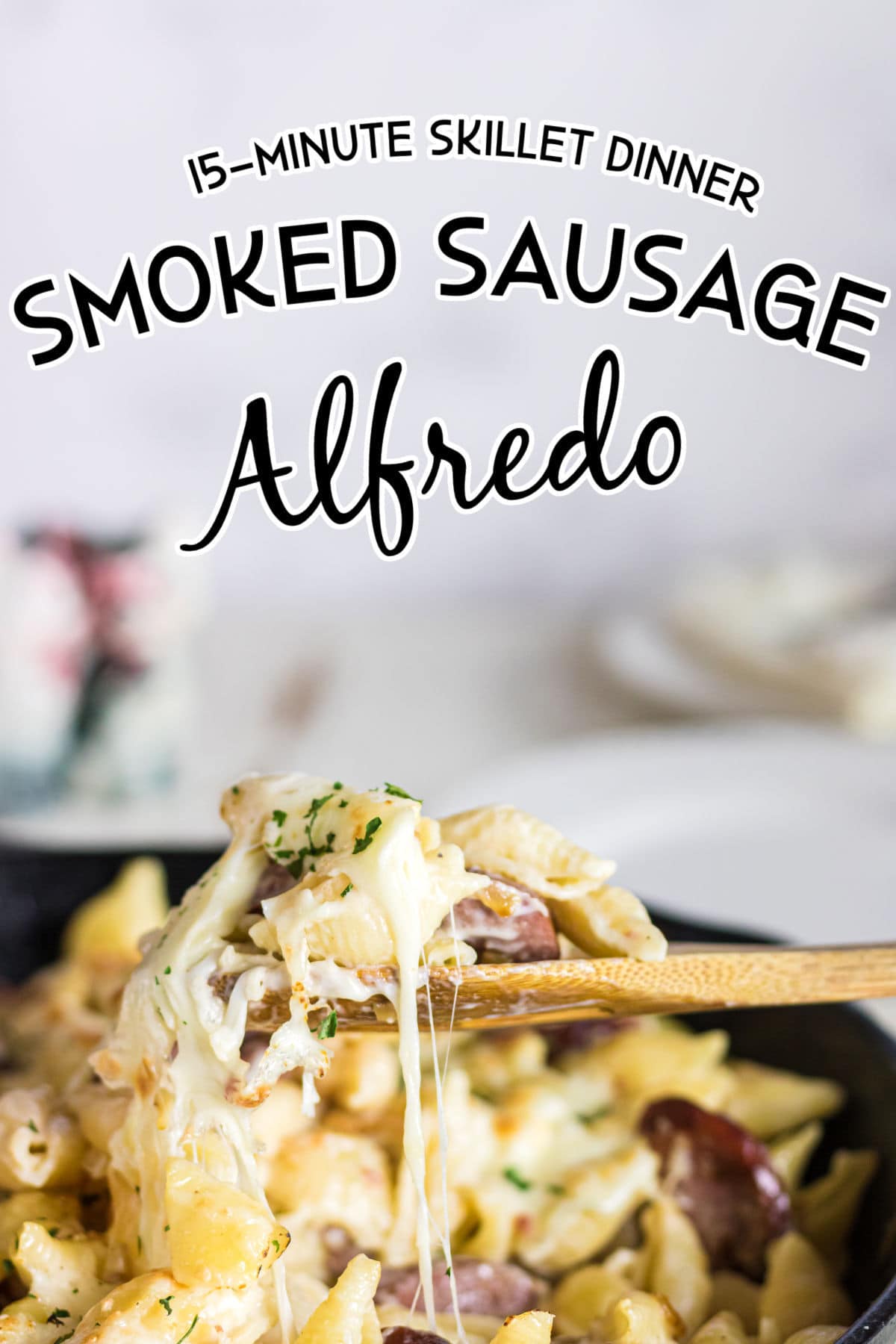 Close up of a spoonful of sausage alfredo with a text overlay for Pinterest.