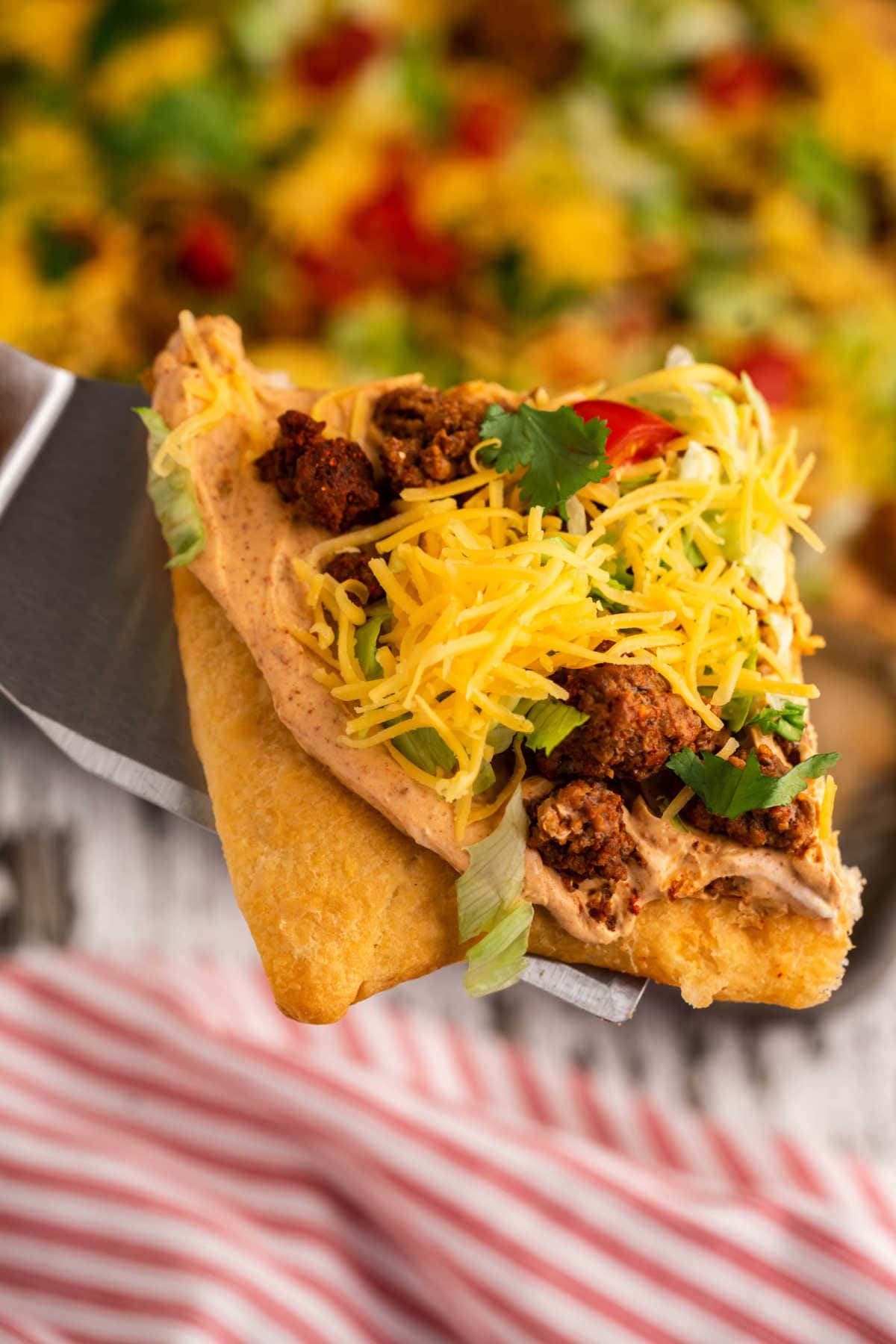 A slice of taco pizza being removed from the pan.