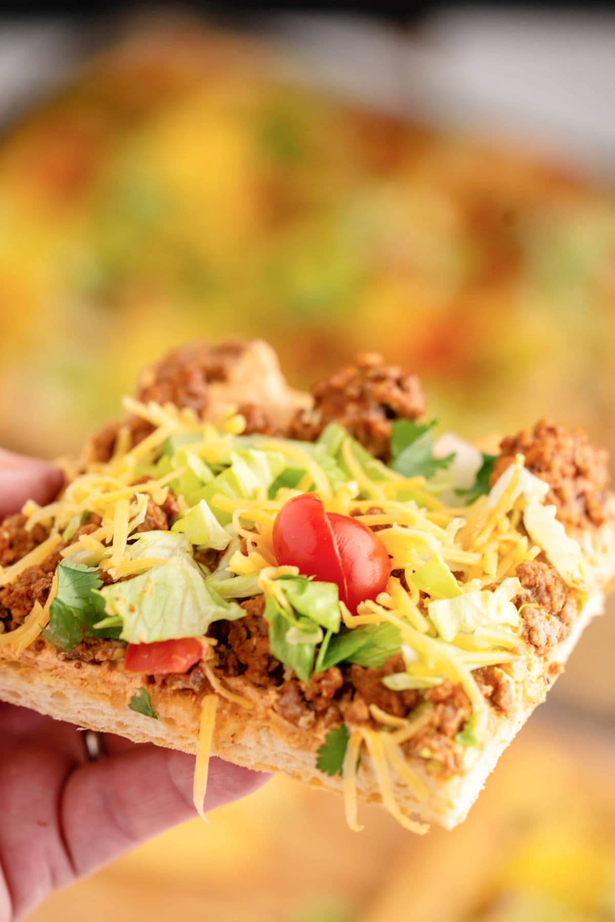 Closeup of a square of taco pizza being eaten.