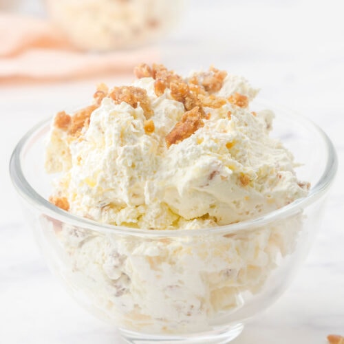 Closeup of a fluffy, creamy pineapple dessert in a glass bowl.