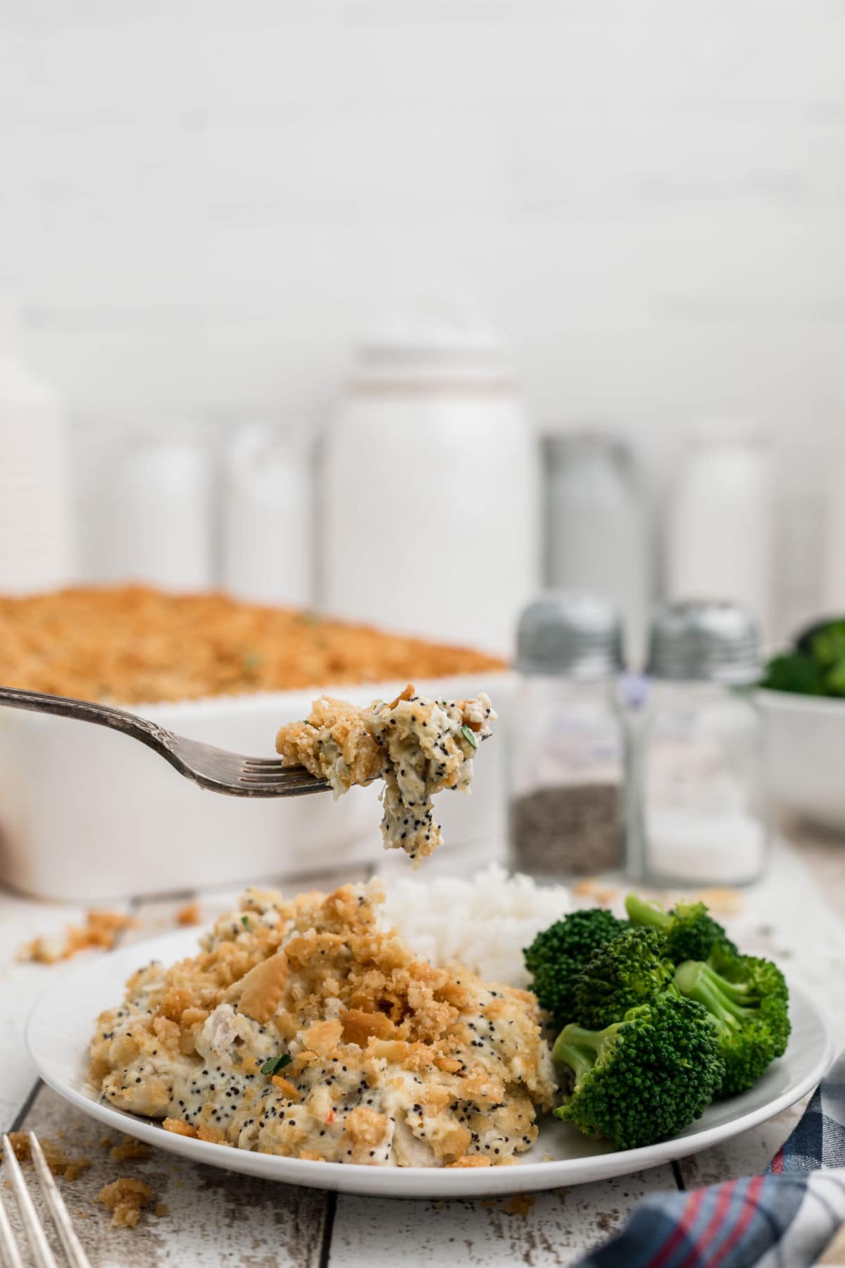 A forkful of poppy seed chicken being lifted from a plate.