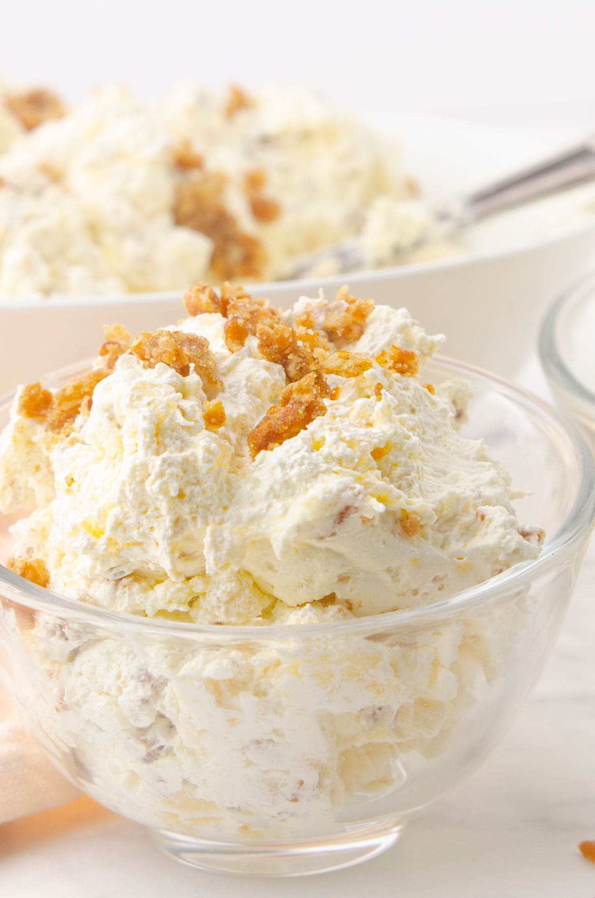 Side view of a glass bowl with a fluffy, creamy pineapple dessert in it.