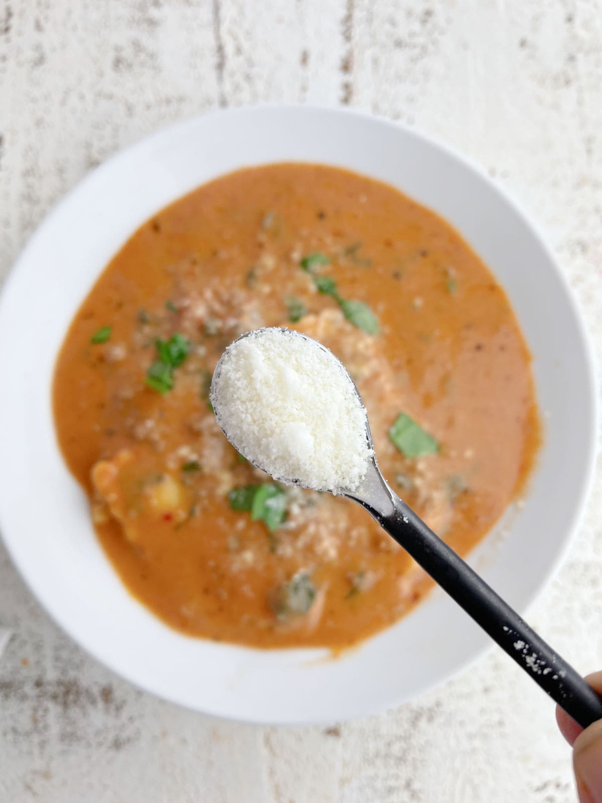 Adding Parmesan to a bowl of soup.