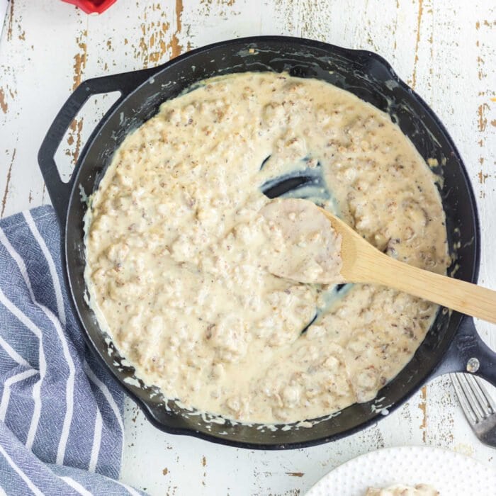 Overhead view of gravy with a wooden spoon in it.