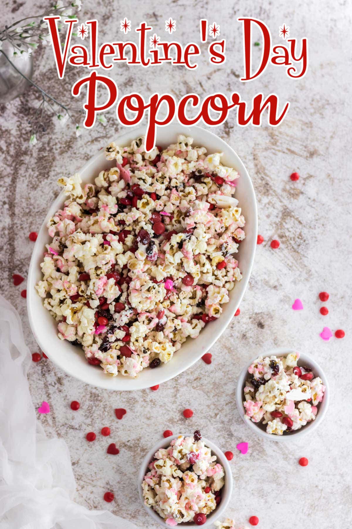 Overhead view of a bowl of popcorn that's been drizzled with white chocolate and has sprinkles added.