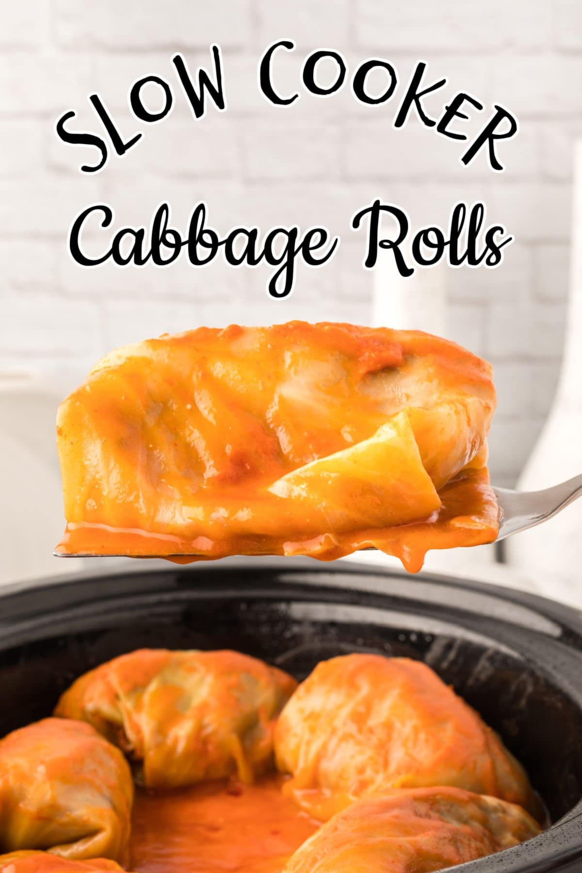 A cabbage roll being removed from the slow cooker.