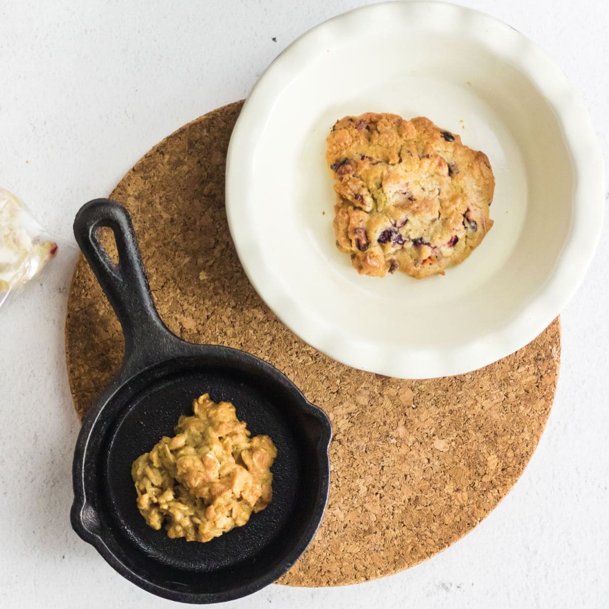 Two pans with a cookie in each cooling on a board.