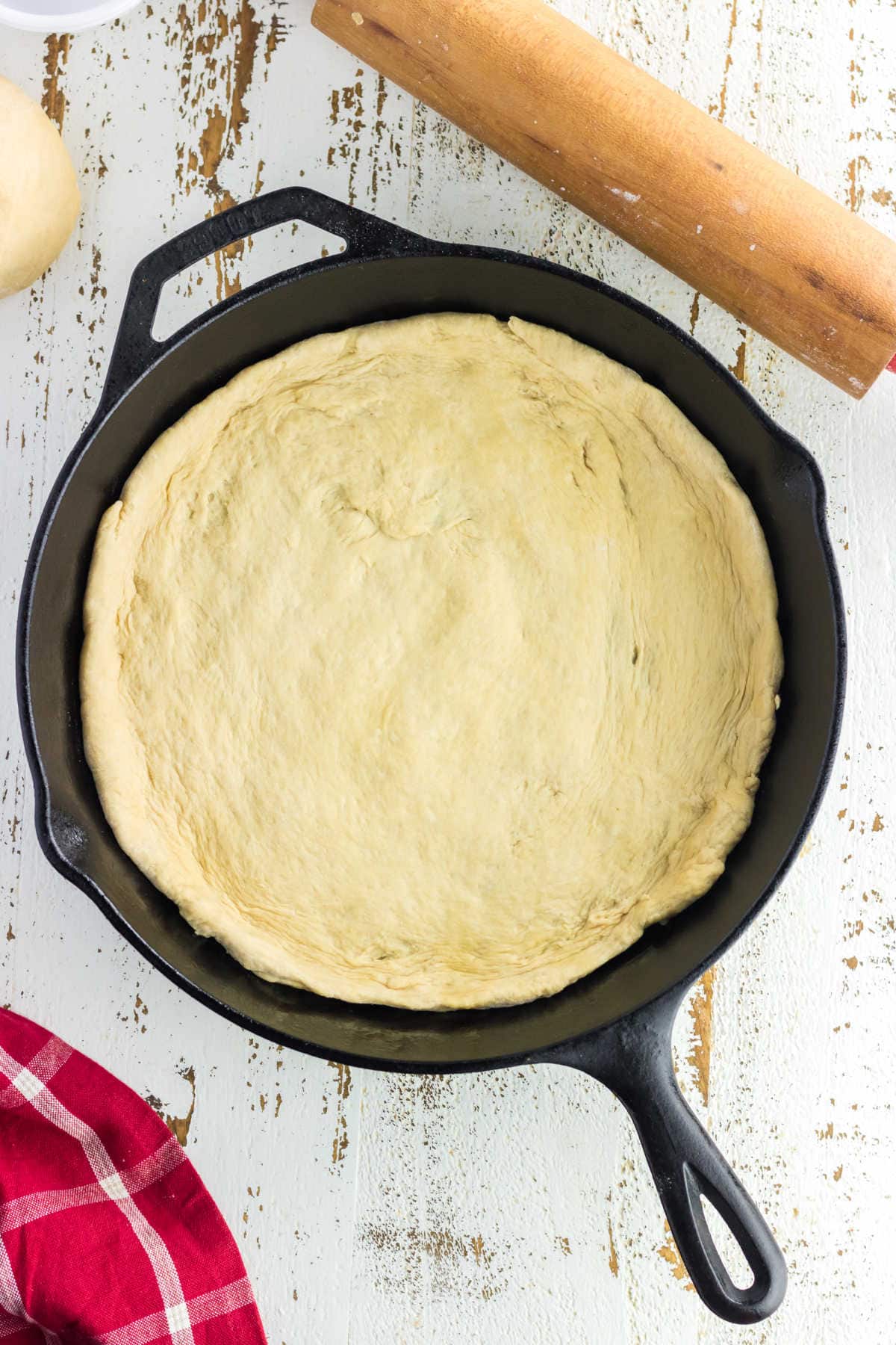 Overhead view of pizza dough in a cast iron skillet.