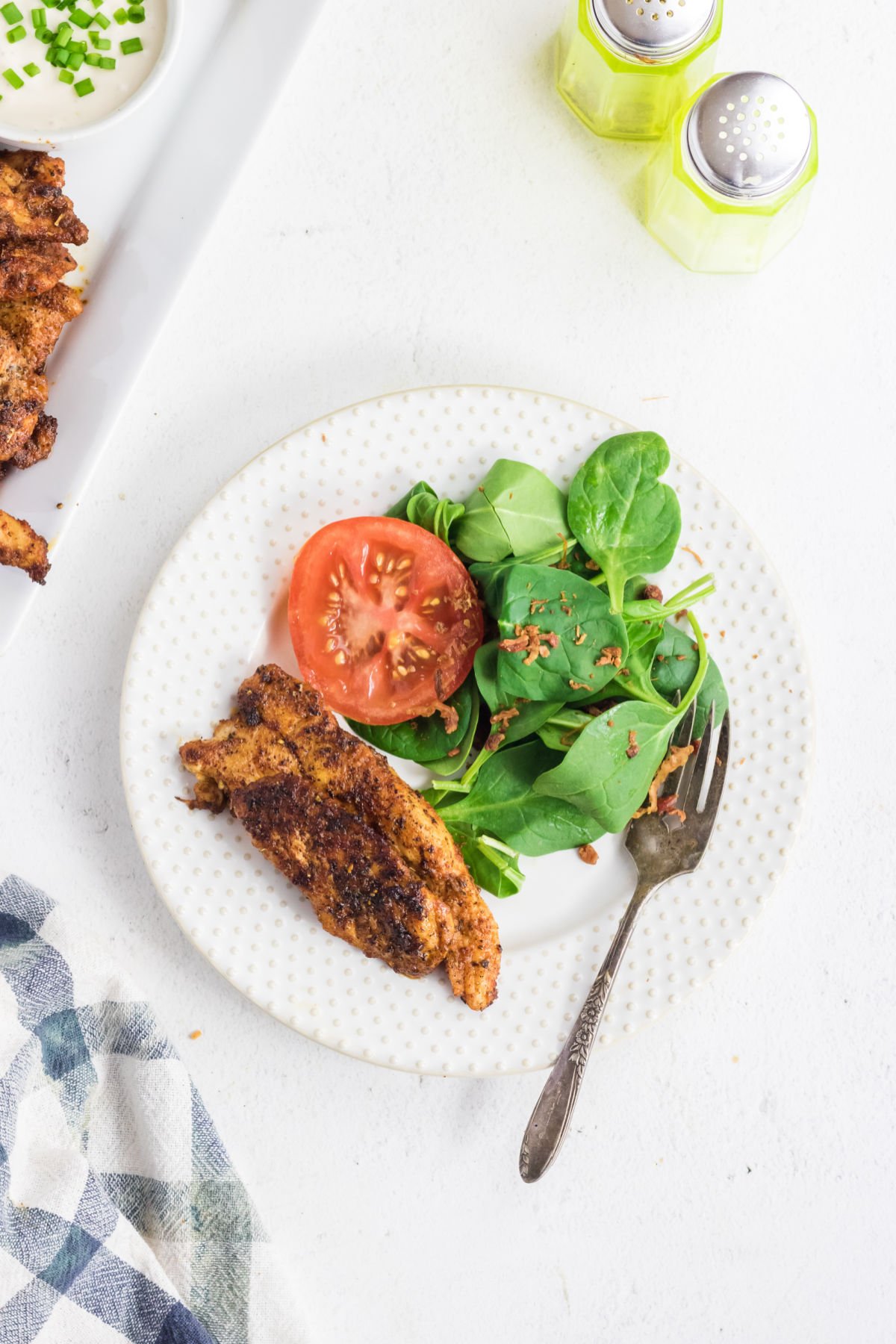 Overhead view of chicken tenders on a plate with a salad.