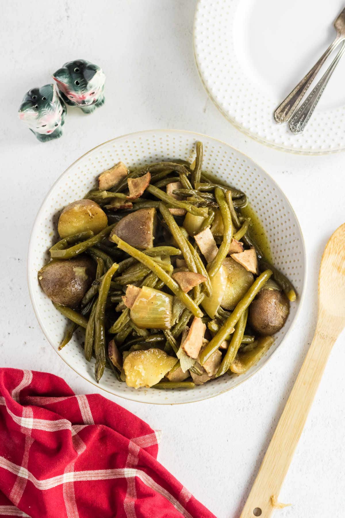 Green beans, potatoes, and ham in a serving dish on the table.