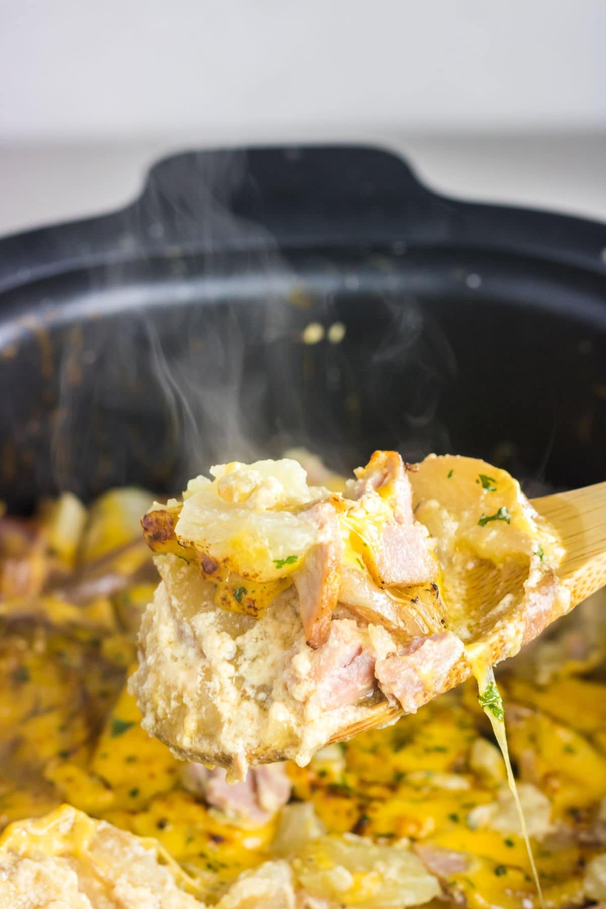 A serving being removed from the slow cooker with steam rising up.