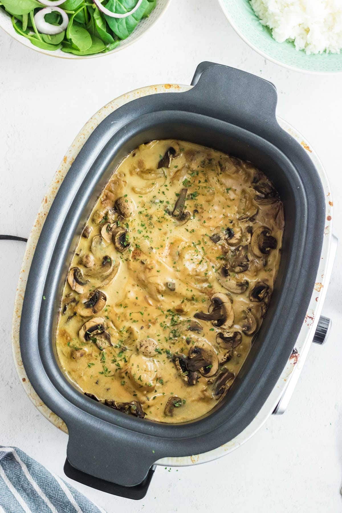 Overhead view of creamy smothered chicken and mushrooms in a crockpot.