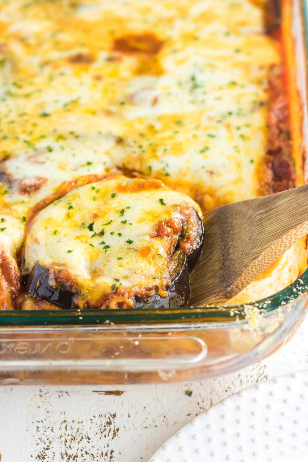 A serving of eggplant parmesan being removed from the dish.