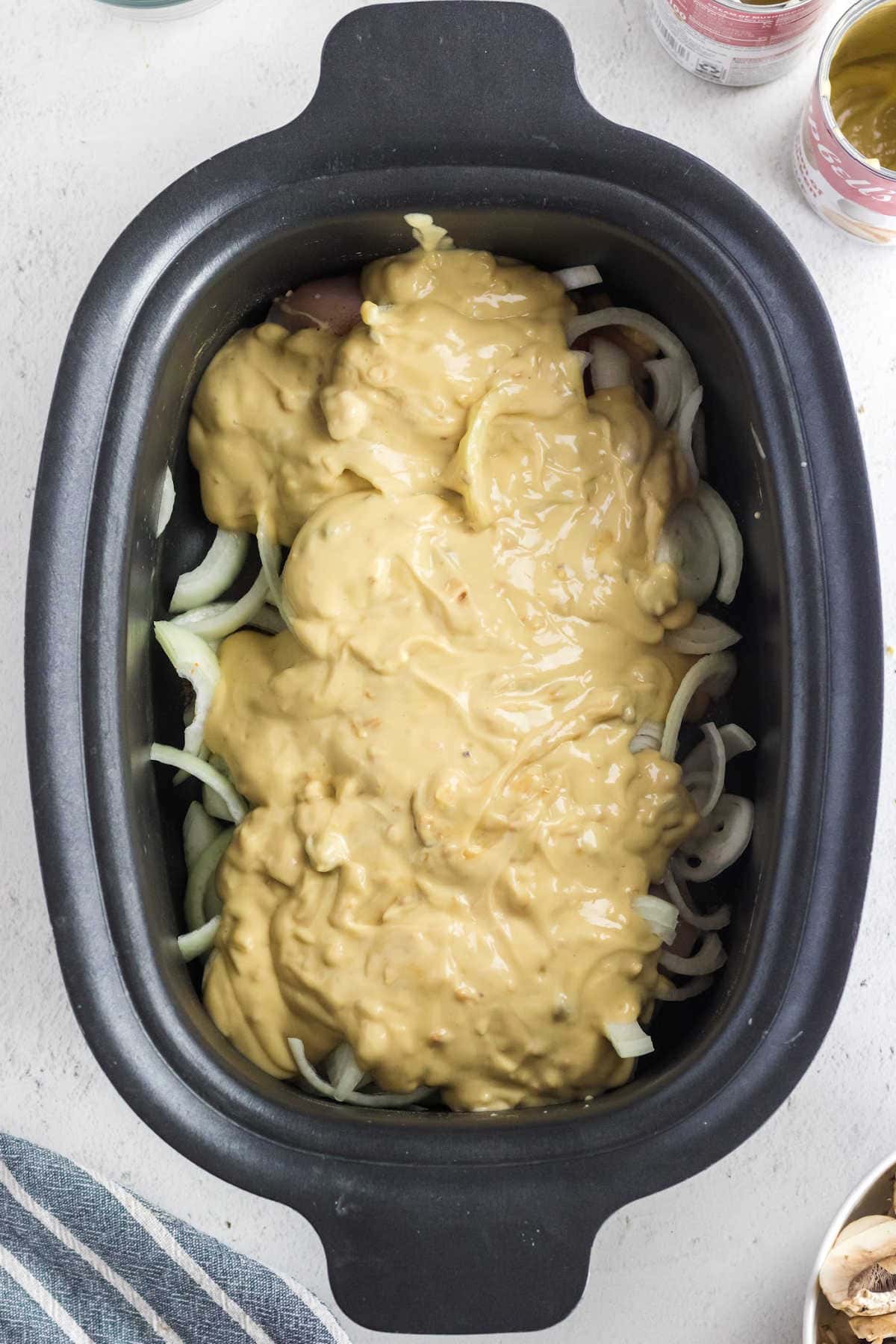 Soup mixture spooned over the chicken in the crockpot.