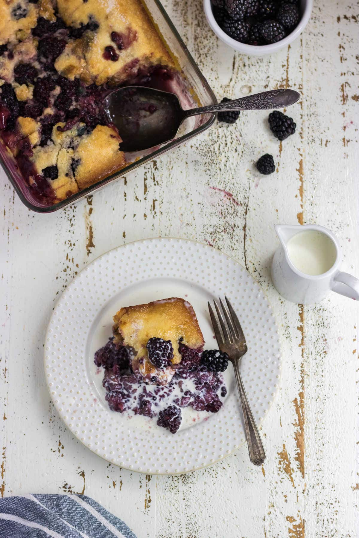 Cobbler on a plate with cream poured over the top.