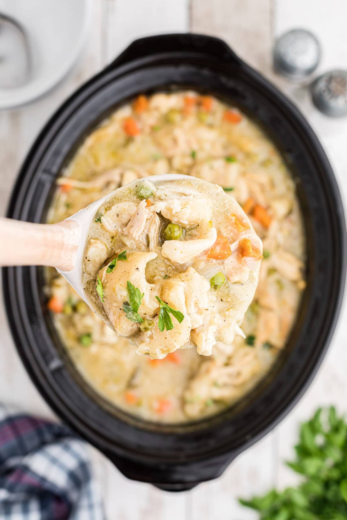 A ladleful of chicken and dumplings being removed from a slow cooker.