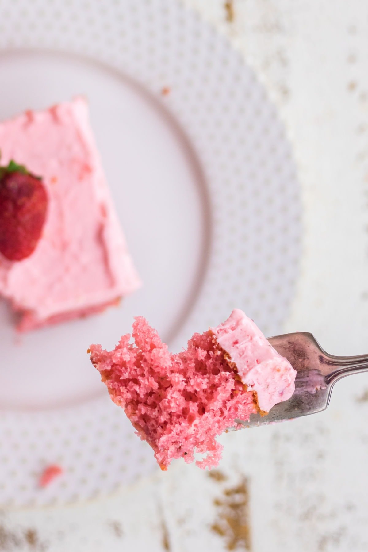 A bite of strawberry cake on a fork.