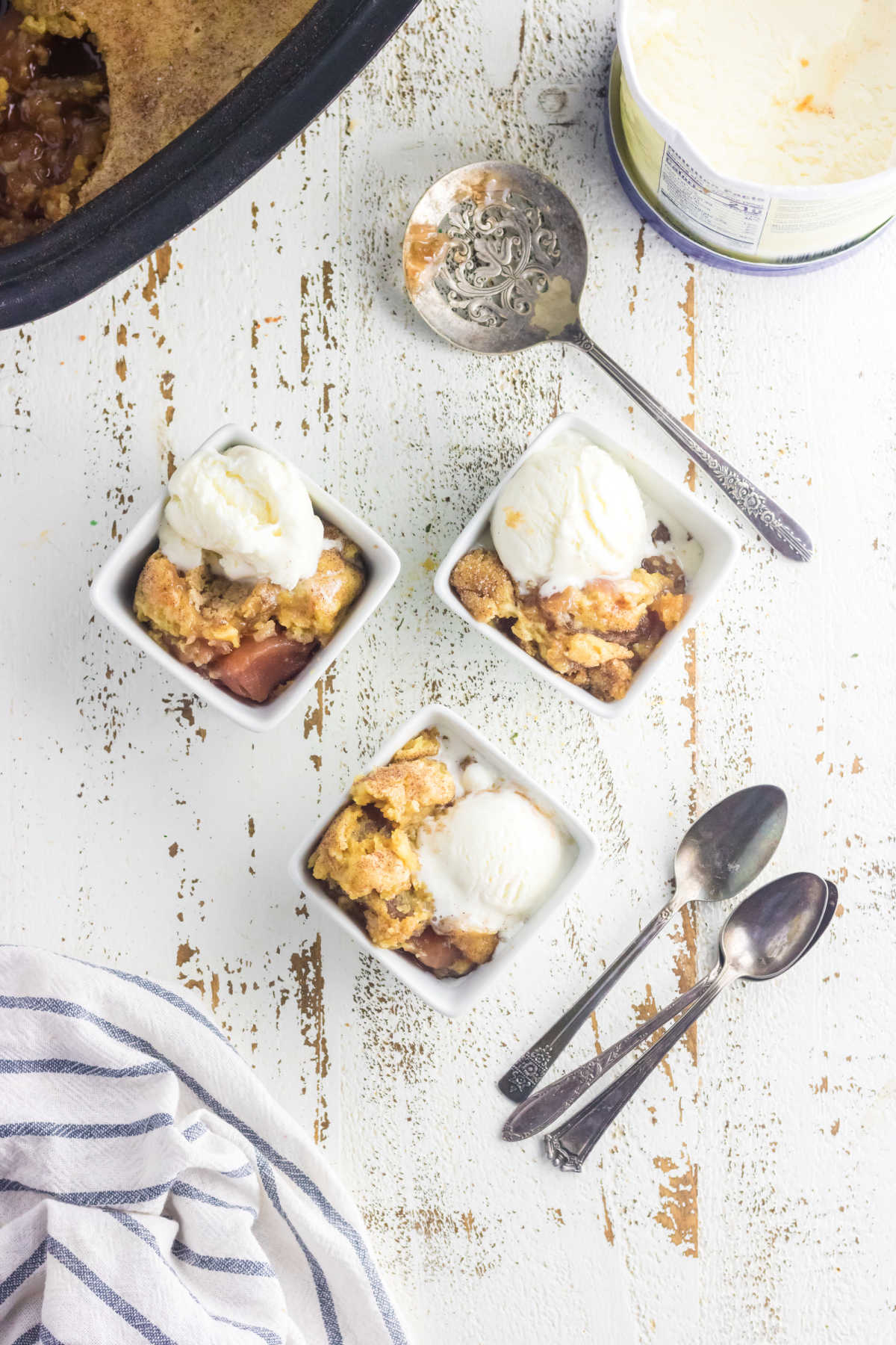 Overhead view of three servings of caramel apple dump cake with ice cream.