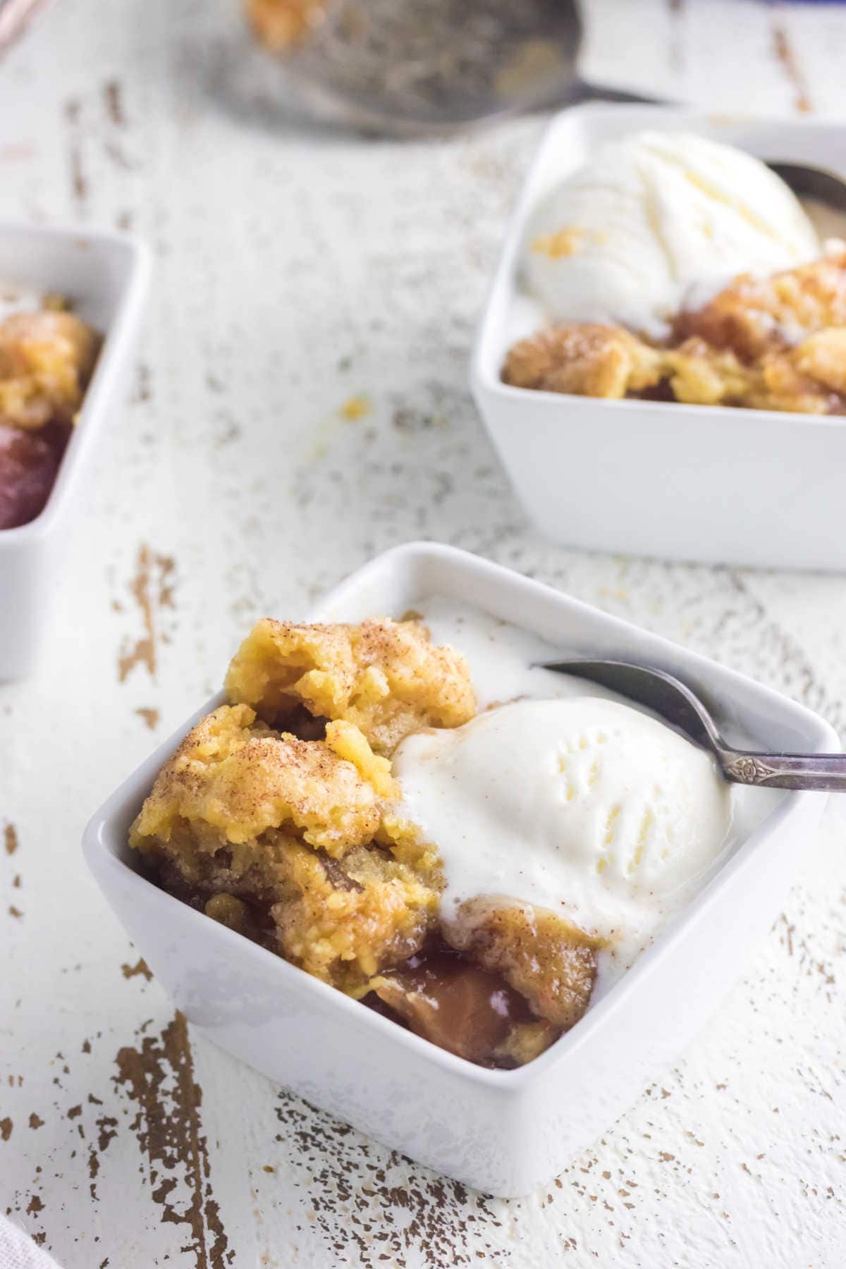 Closeup of the dumpcake showing apples, crust, and melting vanilla ice cream.