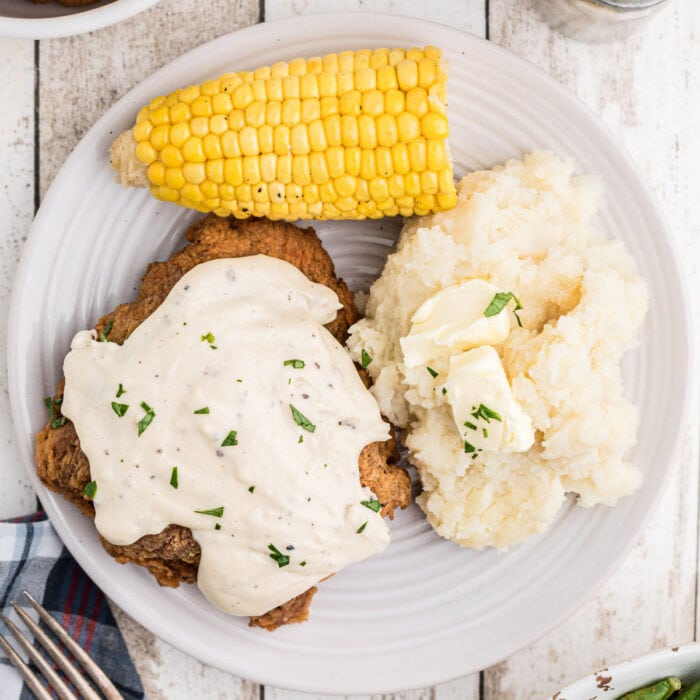 Overhead view of a plate of chicken fried steak, mashed potatoes, and corn.