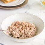 A bowl of ham salad with a spoon in it.