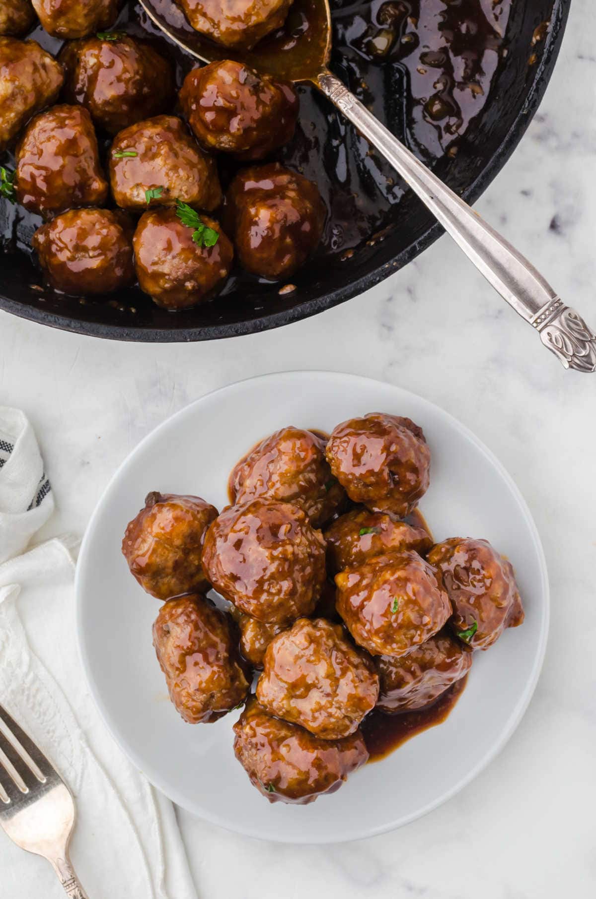 Overhead view of meatballs being spooned into a dish.