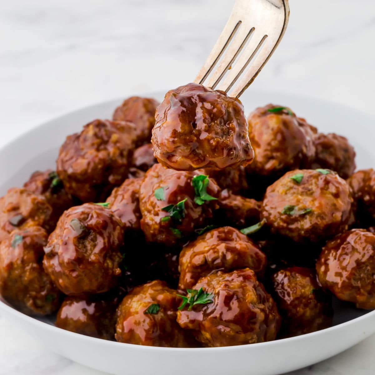 Closeup of a glazed meatball on a fork.