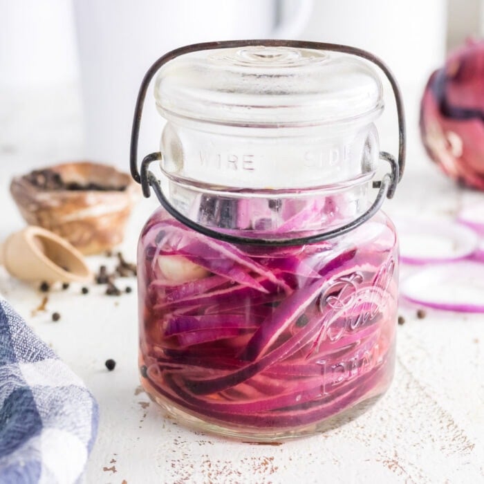 Closeup of pickled onions in a jar for featured image.