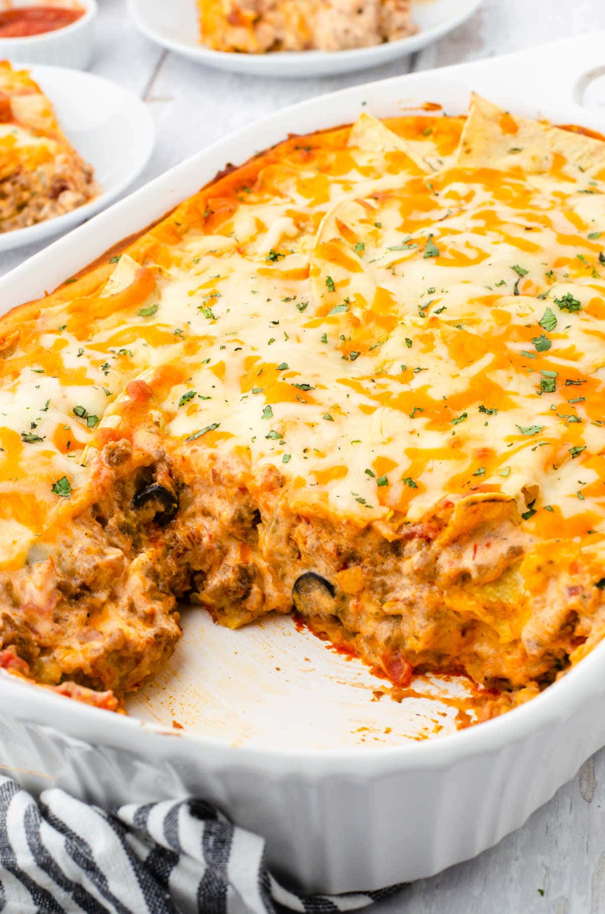 A casserole dish of this Tex-Mex lasagna with a serving removed.
