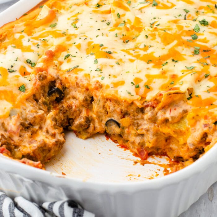 A dish of Mexican lasagna with a serving removed. Feature image.