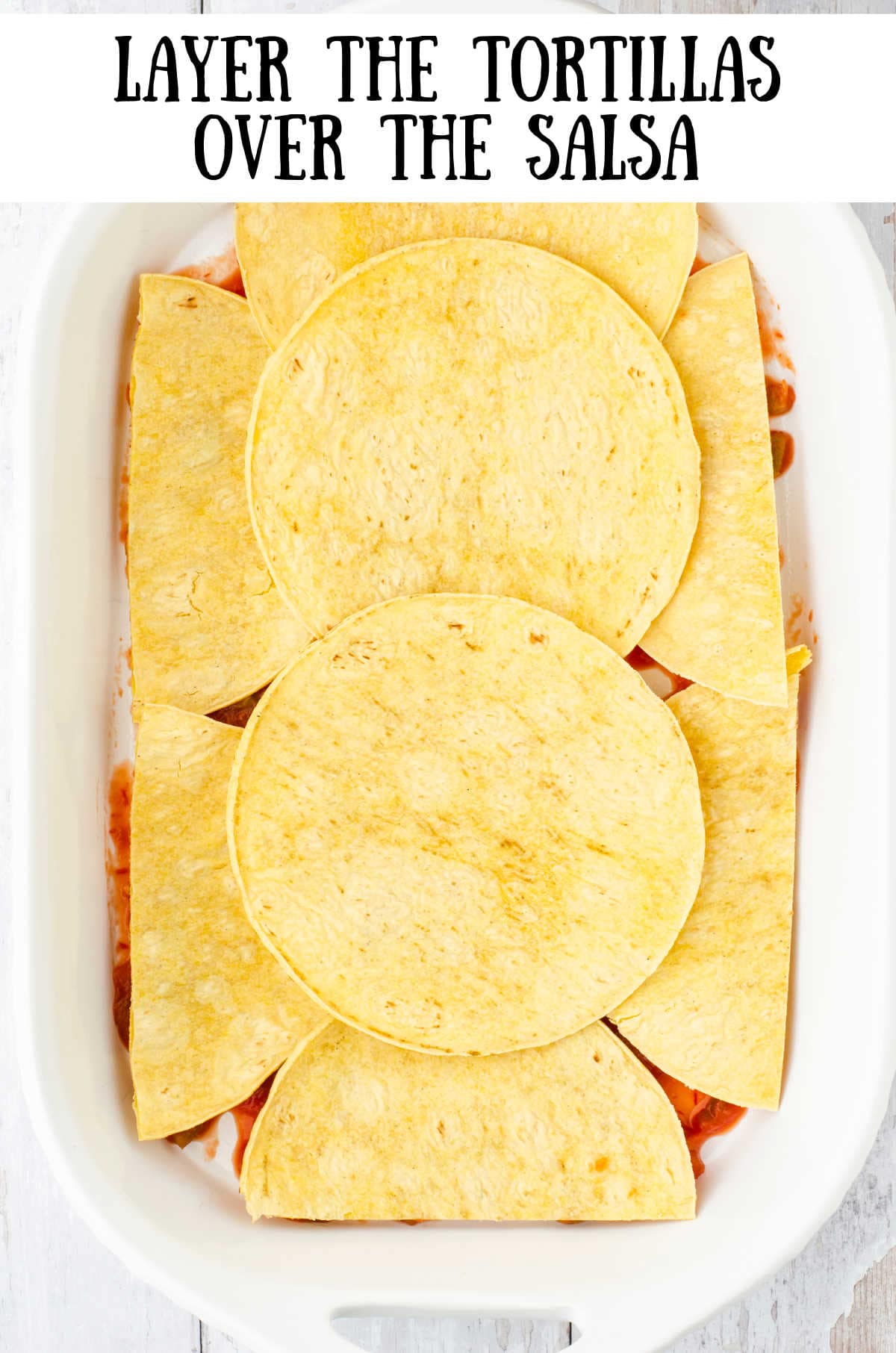 Tortillas cut and fit into the bottom of the casserole dish.