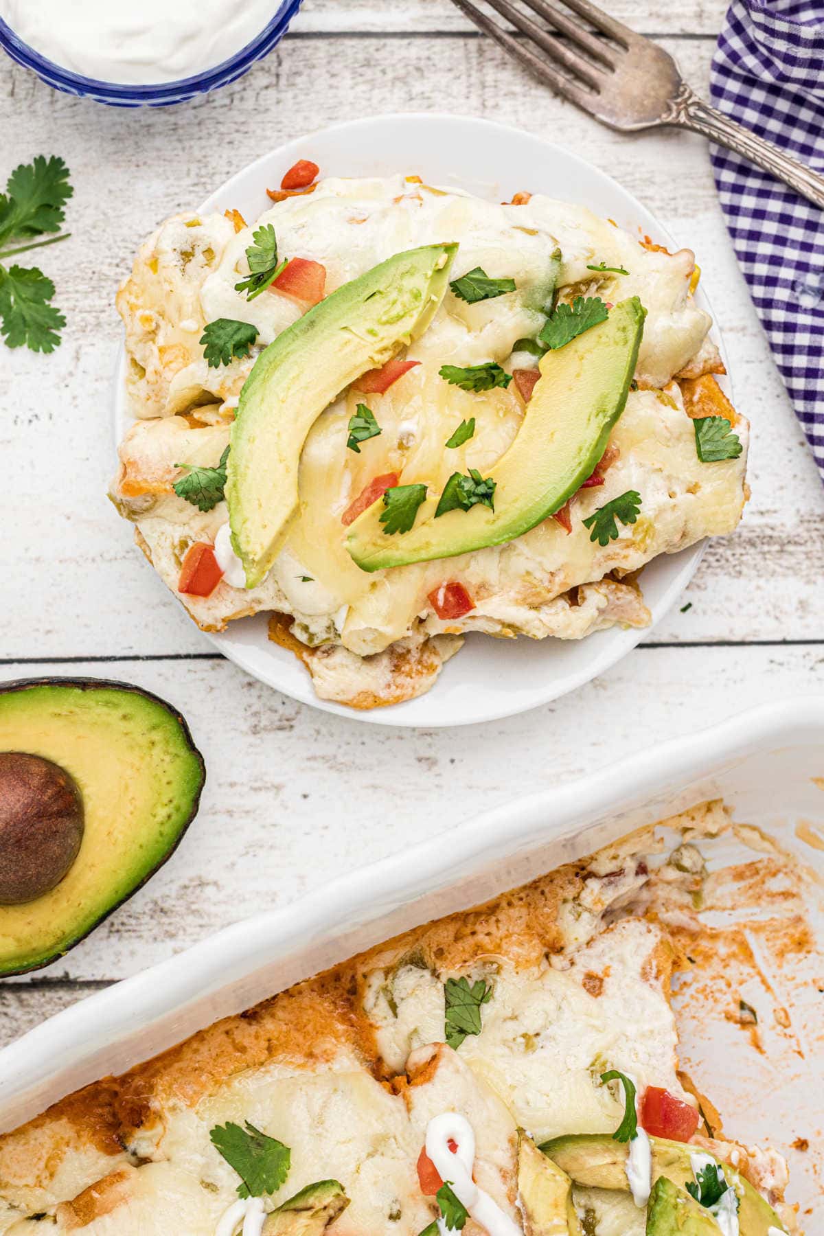 Overhead view of a plate of enchiladas garnished with avocado.