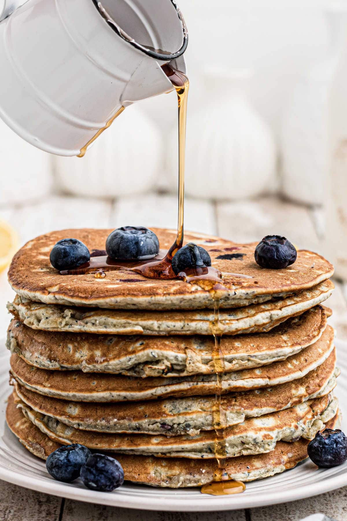 Maple syrup being poured over pancakes.