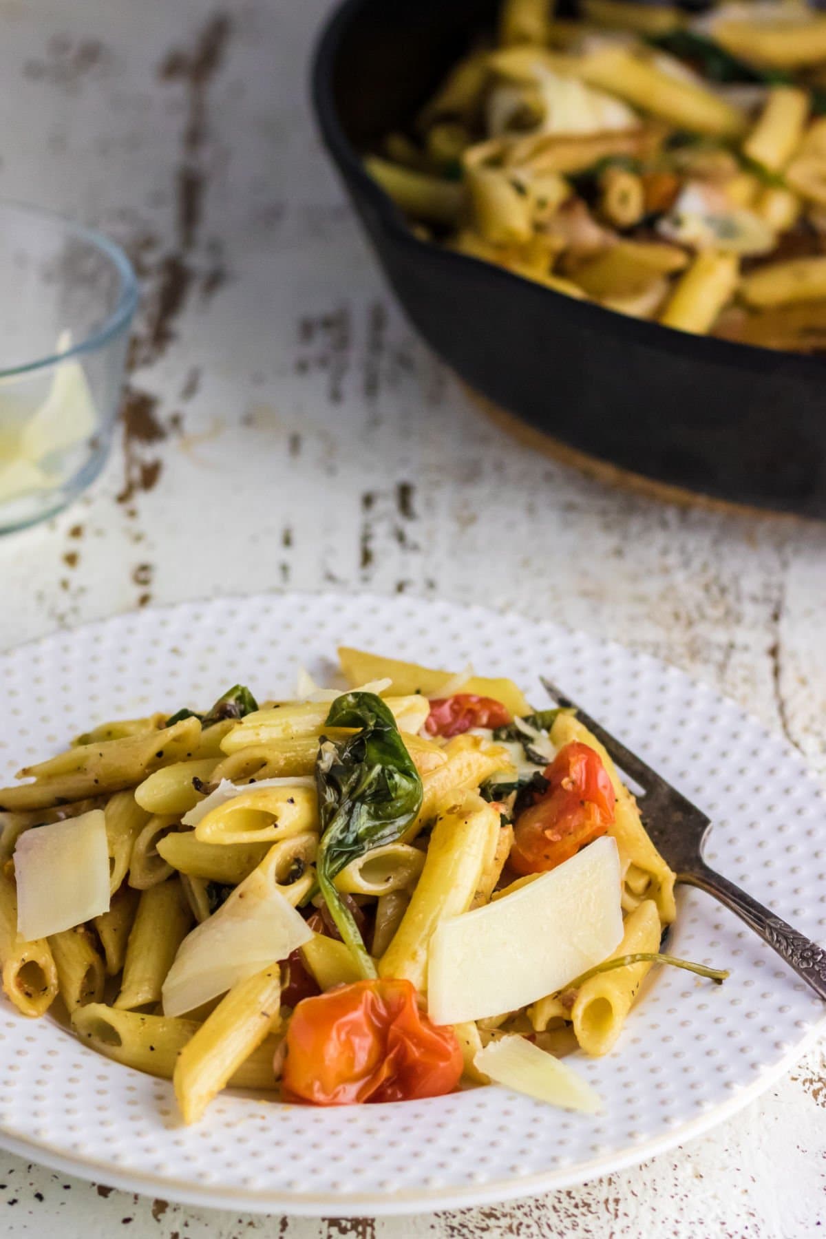 A plate of penne pasta with fresh vegetables.