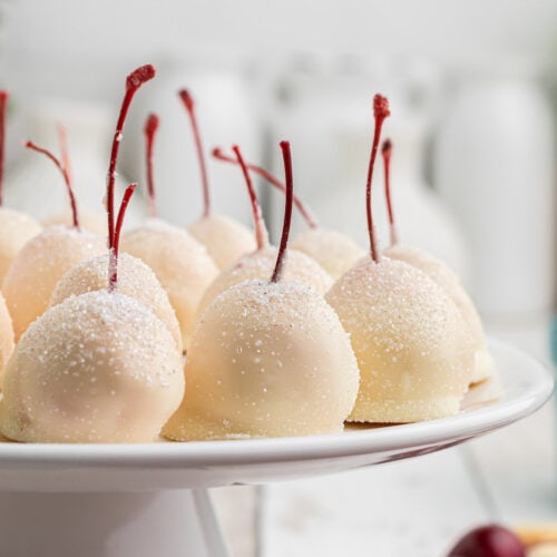 Closeup of white chocolate cherries with stems for featured image.
