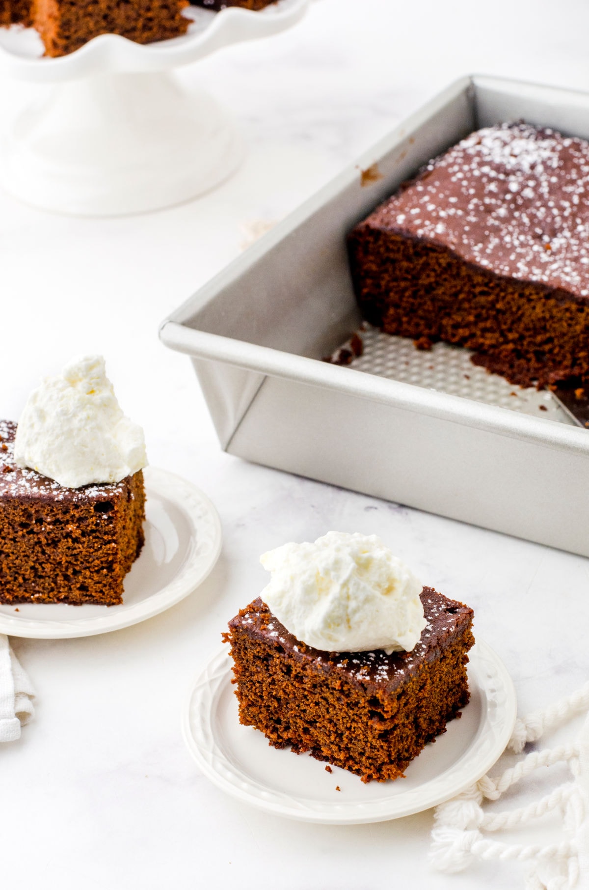 Two servings of gingerbread with whipped cream on top.